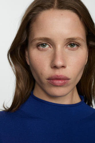Robe bleue à longues manches de MANGO, gros plan sur le modèle aux cheveux bruns et au haut bleu.