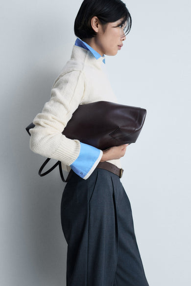 Witte trui met ronde hals van MANGO, gedragen met een blauw overhemd en wijde pantalon, zijaanzicht.
