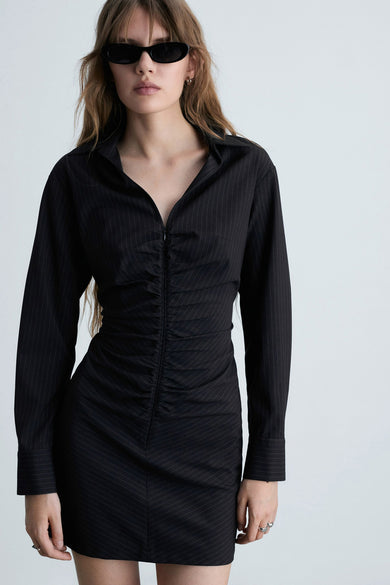 Robe bleue à longues manches de MANGO, avec une rayure blanche et des talons aiguilles noirs.