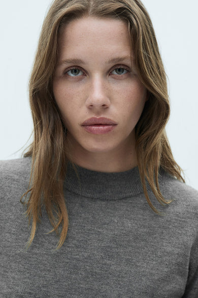 Grijze trui met ronde hals van MANGO, close-up shot met model.
