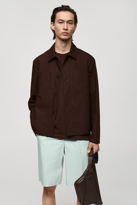 Manteau court rouge de MANGO, vu de derrière, avec des short bleus et un sac marron.