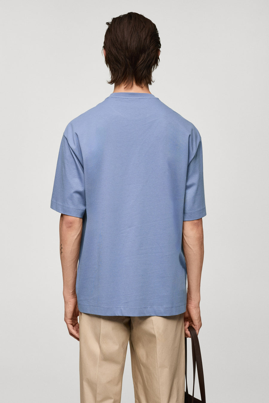 Paars T-shirt met korte mouwen van MANGO, achterkant, gecombineerd met beige pantalon en een bruine tas.
