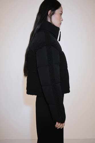 Manteau court multicolore de MANGO avec des accents en fourrure, associé à une jupe noire et des bottes en cuir.
