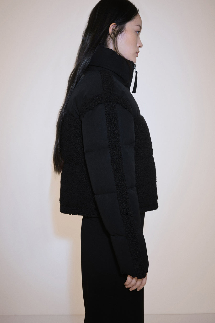Manteau court multicolore de MANGO avec des accents en fourrure, associé à une jupe noire et des bottes en cuir.