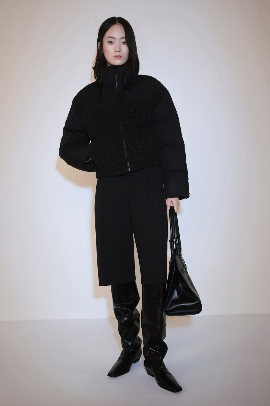 Manteau court multicolore de MANGO, avec des manches bouffantes, associé à une jupe noire et des bottes noires hautes.