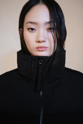 Manteau court noir de MANGO avec un col haut et une fermeture éclair à l'avant.