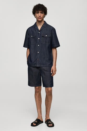 Denim jeansshort in mid blue denim van MANGO, met een bijpassend denim overhemd en zwarte sandalen.
