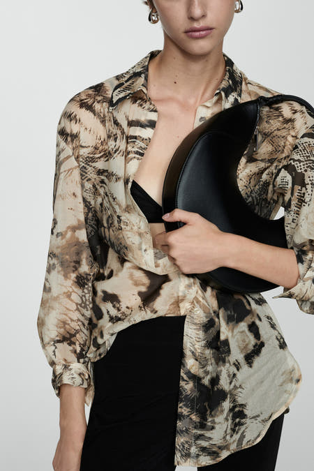 Beige blouse met lange mouwen van MANGO, met een dierenprint en gedragen met een zwarte bh en rok.

