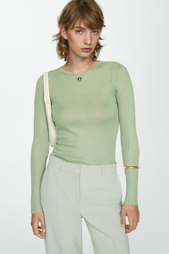 Groene trui met ronde hals van MANGO, gecombineerd met een lichte pantalon en gouden armband.
