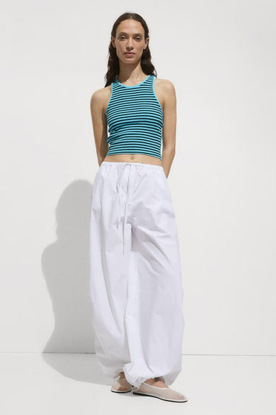 T-shirt bleu à rayures de MANGO, associé à des pantalons blancs larges et des chaussures transparentes.