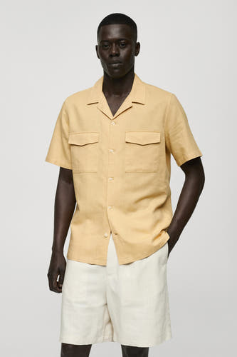Geel, korte mouwen hemd van MANGO, met borstzakken en gedragen met een witte short.
