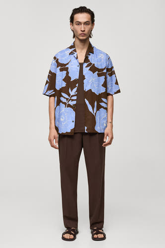 Bruin overhemd met korte mouwen van MANGO, met een blauw bloemenpatroon, gecombineerd met bruine broek en sandalen.
