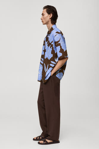 Bruin overhemd met korte mouwen van MANGO, met een blauw bloemenpatroon, gecombineerd met bruine broek en sandalen.