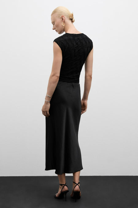 Zwart korte mouwen blouse met textuur van MANGO, achterzijde weergegeven, gedragen met zwarte rok en hakken