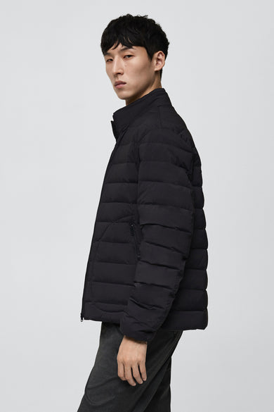 Korte grijze jas van MANGO, met horizontale stiksels en gedragen over een donkere broek.
