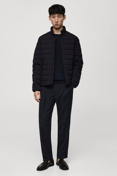 Korte blauwe jas van MANGO, gedragen met een donkere trui en pantalon, en zwarte schoenen.
