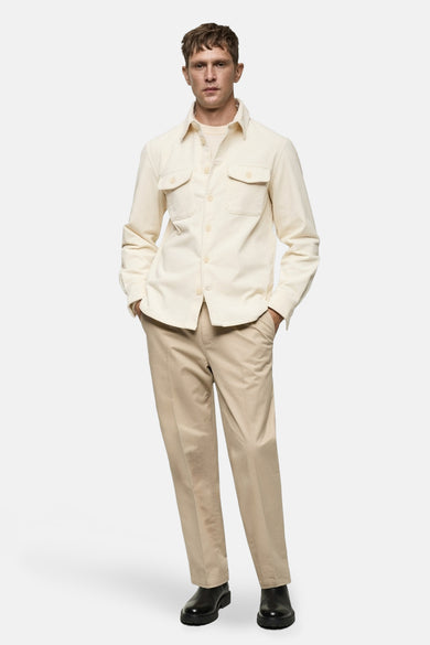 Wit overhemd met lange mouwen van MANGO, met borstzakken en gedragen met beige pantalon en zwarte schoenen.
