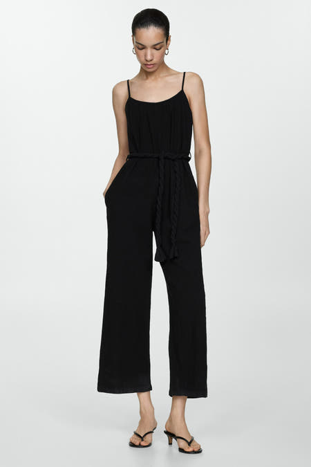 Zwarte jumpsuit van MANGO met een gevlochten ceintuur en wijde pijpen, gecombineerd met teenslippers met hak.
