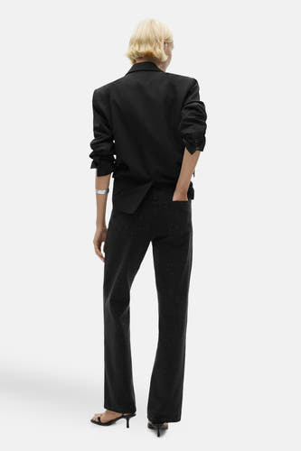 Donkergrijze straight jeans van MANGO, met subtiele spikkels en gecombineerd met een zwarte blazer en sandalen.
