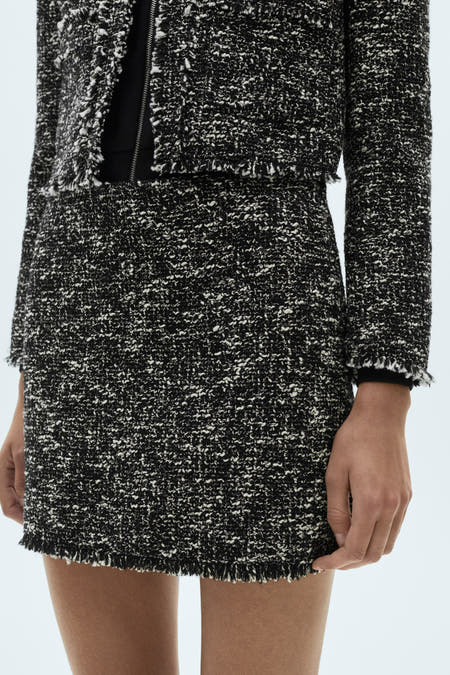 Multikleurige korte rok van MANGO, met gerafelde details aan de zoom en een getextureerd tweed-achtig patroon.
