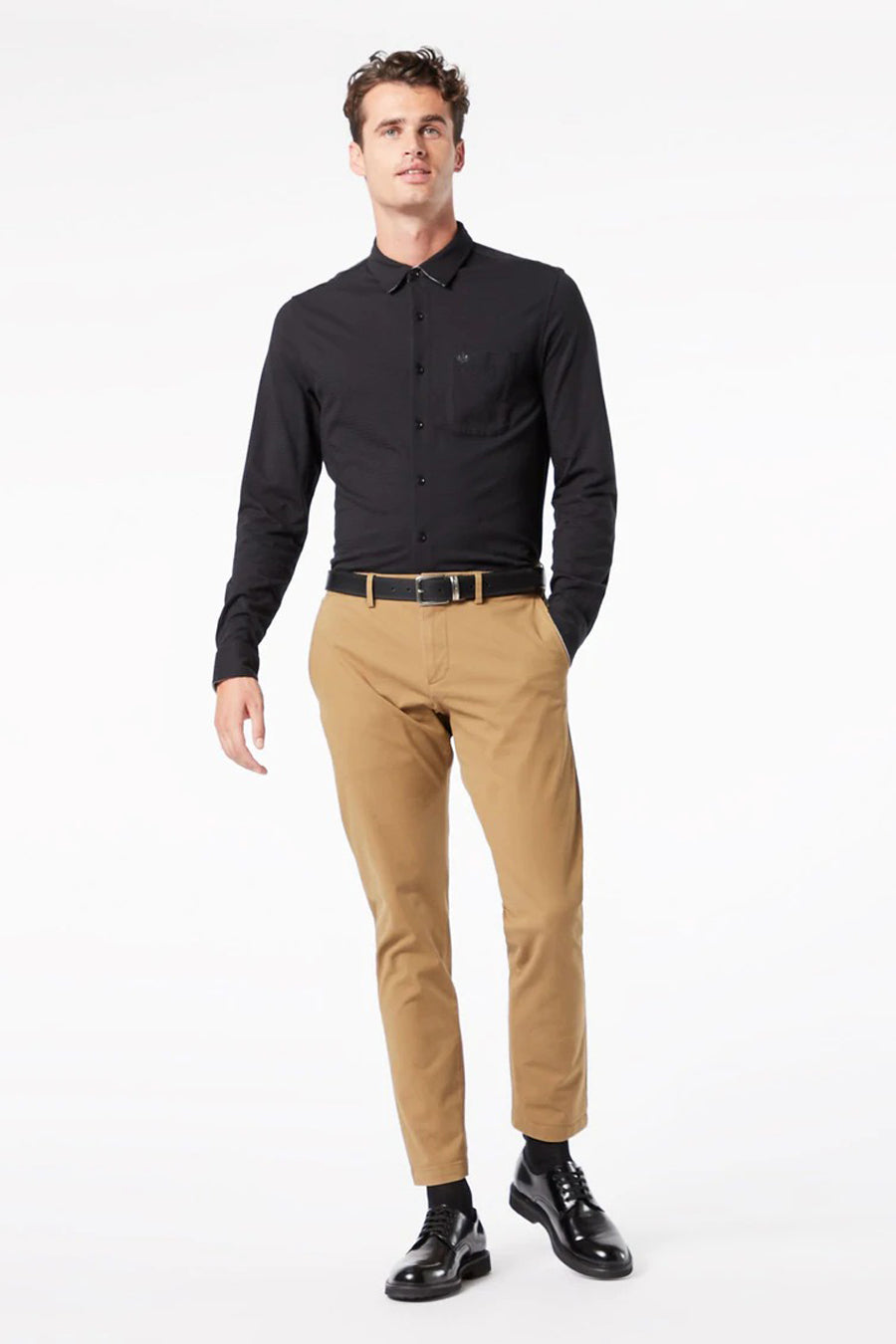 Homme en t-shirt blanc et pantalon marron.