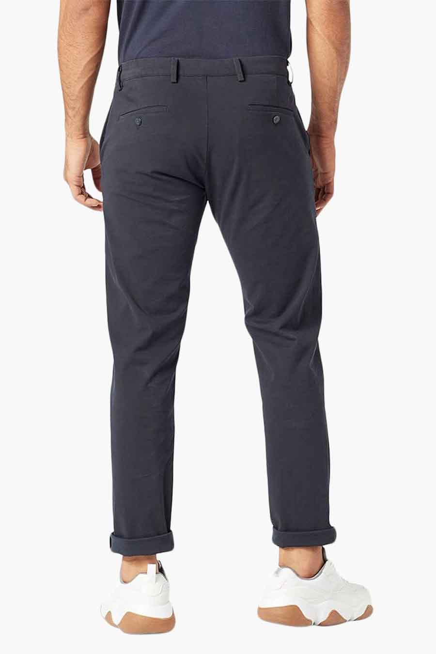 Blauwe chino van DOCKERS, gezien van achteren, met opgerolde pijpen en witte schoenen.
