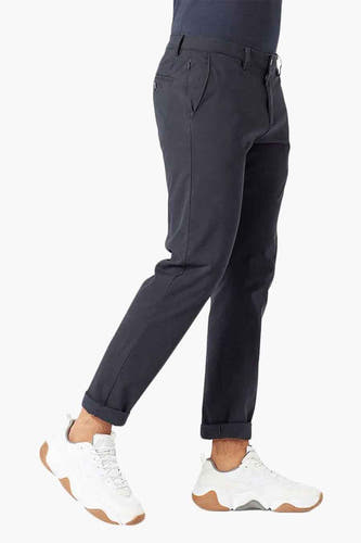 Blauwe chino van DOCKERS, gezien van de zijkant met opgerolde pijpen en witte sneakers.
