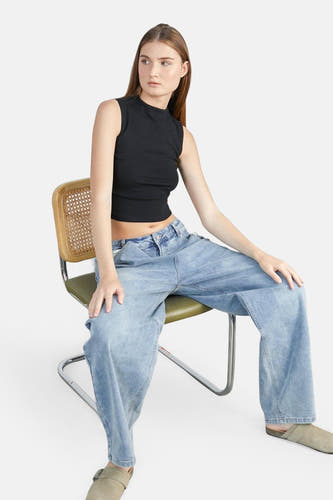 Jean décontracté en denim bleu moyen parmi 24 couleurs, porté avec un haut noir et des baskets.
