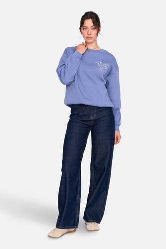 Donkerblauwe denim jeans wide van 24 colours gmbh, met wijde pijpen en gecombineerd met een blauwe sweater en beige schoenen.