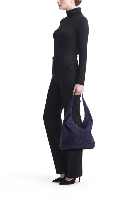 Donkerpaarse suède schoudertas van Access®, zachte hobo-stijl gedragen door model in zwart.