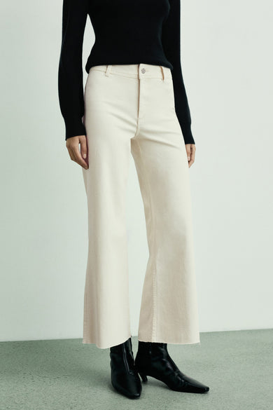 Off-white denim wide jeans van MANGO, met raw-cut zoom, gecombineerd met zwarte top en laarsjes.
