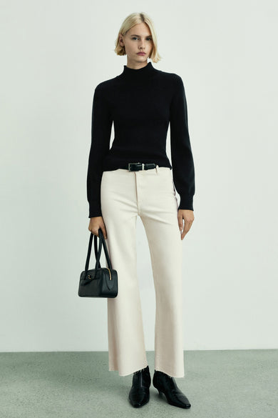 Off white wijde jeans van MANGO, gecombineerd met zwarte coltrui, riem en handtas, met zwarte laarsjes.