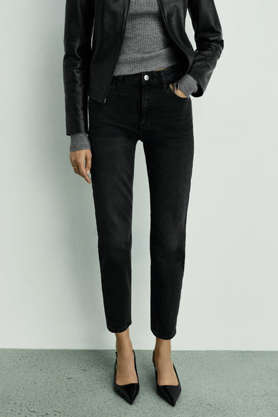 Donkergrijze mom jeans van MANGO, gecombineerd met een grijze trui en een zwarte leren jas.