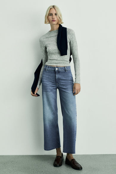 Donkerblauwe wijde jeans van MANGO, gecombineerd met een grijze top en bruine schoenen.

