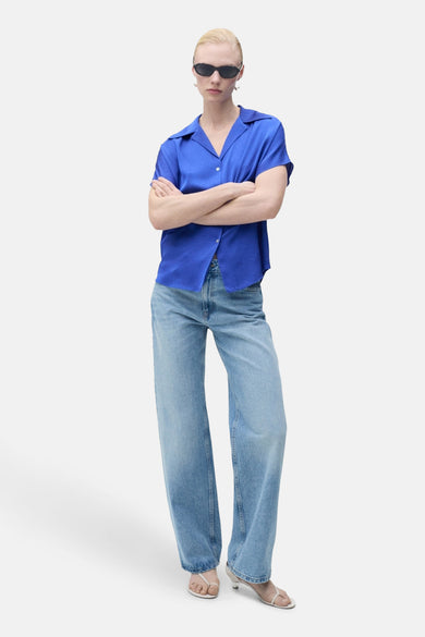 Blauw hemd met korte mouwen van MANGO, gedragen met een losse jeans en witte sandalen.
