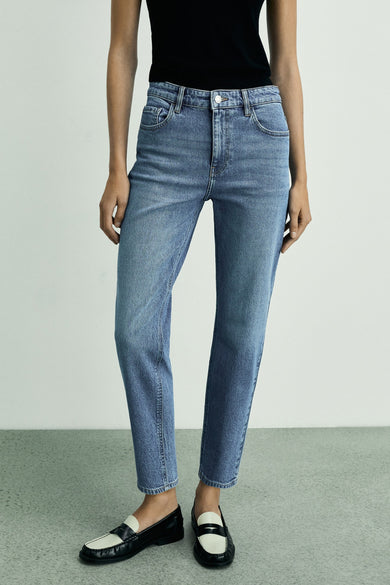 Middenblauwe mom jeans van MANGO, gedragen met een zwarte top en zwart-witte loafers.
