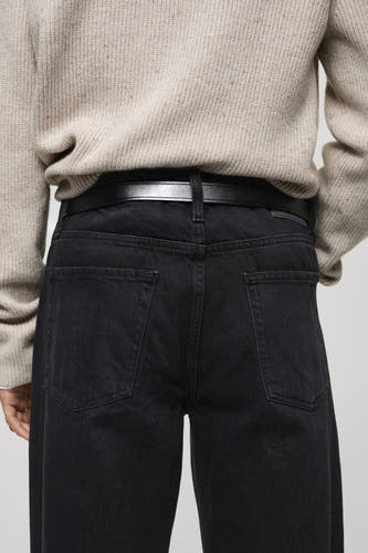 Jean droit en denim gris foncé de MANGO, avec ceinture et chemise beige.