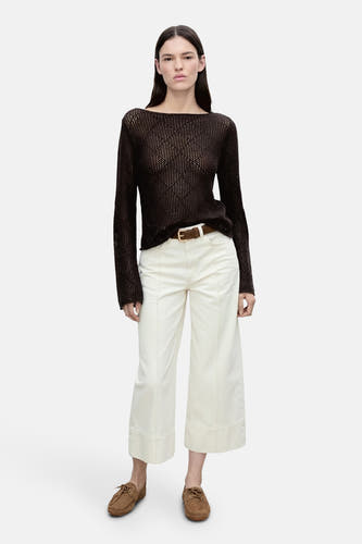 Bruine trui met ronde hals van MANGO, gedragen met witte broek, bruine riem en mocassins.