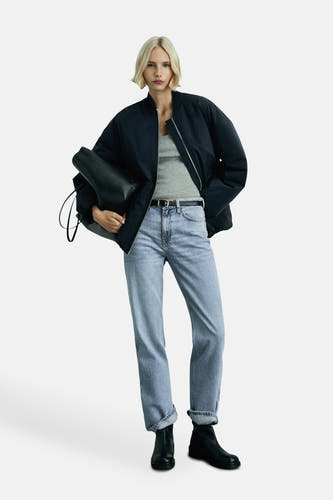 Lichtblauwe rechte jeans van MANGO, gedragen met een zwarte jas en een grijze top.