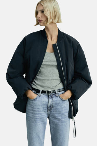 Lichtblauwe straight jeans van MANGO, gedragen met een zwarte riem en een grijze top onder een donkerblauw jack.