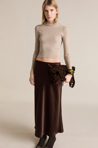 Gilet beige avec col rond de MANGO, associé à une jupe marron et un sac.