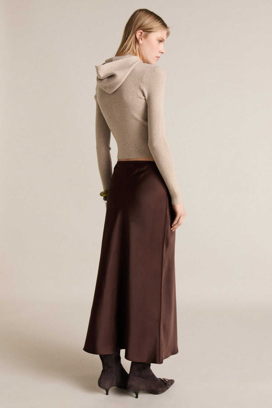 Beige trui met ronde hals van MANGO, met lange mouwen en fijne ribbels, gedragen met een bruine rok en laarzen.
