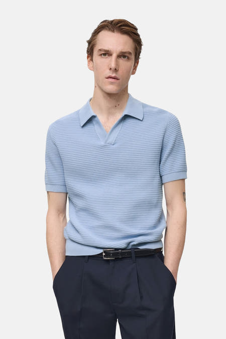 Blauw poloshirt met korte mouwen van MANGO, gedragen met een donkere broek met riem, in een rechte pose.
