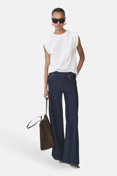 T-shirt blanc sans manches de MANGO, porté avec des jeans larges et un sac marron.