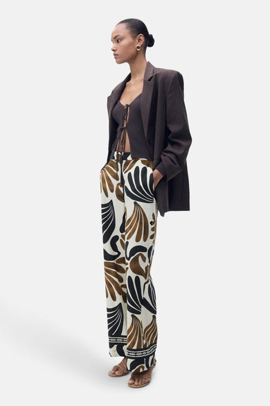 Pantalon multicolore de MANGO avec un motif de feuilles frappant, associé à une chemise tricotée marron et un blazer marron.