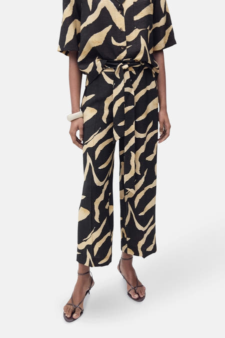 Zwarte broek van MANGO met beige zebraprint en strikceintuur, gecombineerd met een bijpassende blouse en sandalen.
