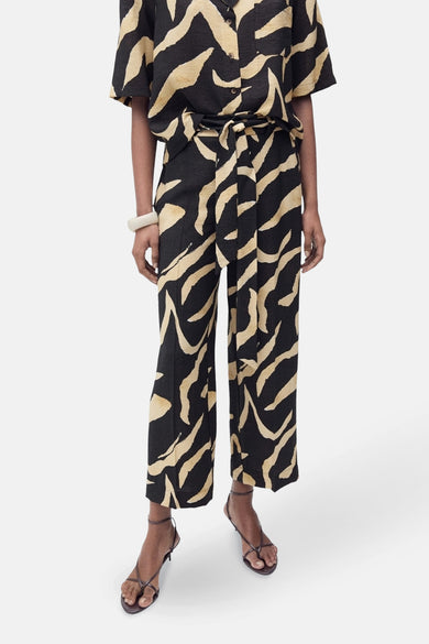 Pantalon noir de MANGO, avec un imprimé zèbre abstrait beige et une cecece correspondante.