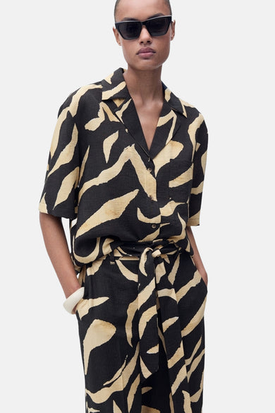 Pantalon noir de MANGO, avec un imprimé zèbre beige et une ceinture nouée.