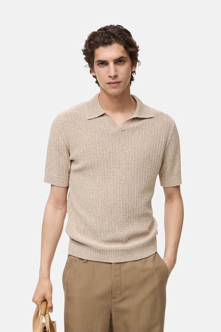 Polo beige à manches courtes de MANGO, avec une subtile texture et porté avec un pantalon marron.
