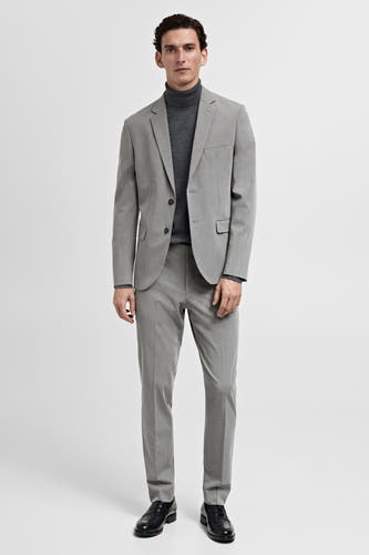 Grijze blazer van MANGO, gedragen met een donkergrijze coltrui en grijze pantalon, met zwarte leren schoenen.
